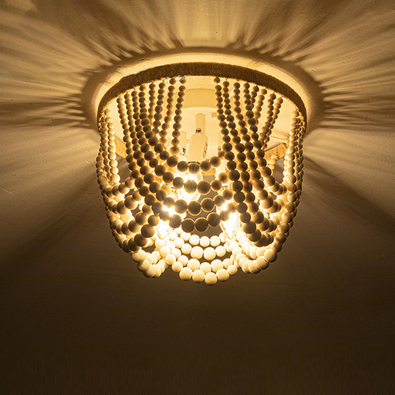 ستارة دائرية تقليدية عتيقة مصنوعة من خرز خشبي وأجزاء من نبات السيزال، مزودة بثلاثة مصابيح سقفية مثبتة في غرفة النوم